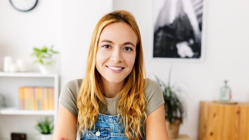 Young woman with long blonde hair smiling seated in a room