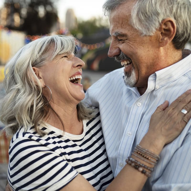Older couple hugging and laughing together.