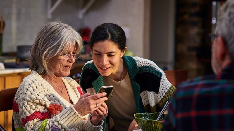 two women smiling and looking at a mobile phone