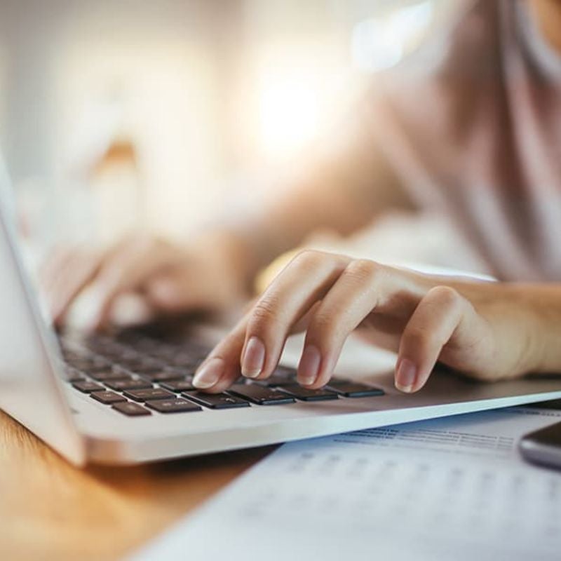woman's hands typing on a laptop