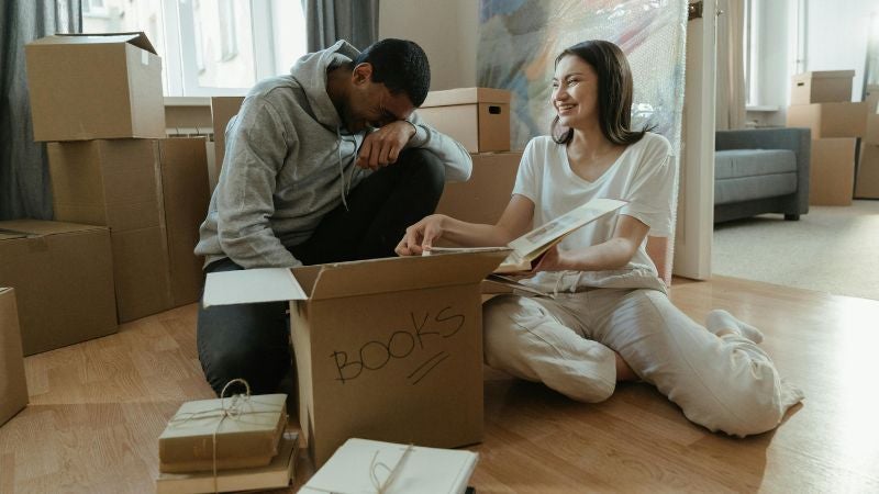 couple sat down with open box on the floor laughing